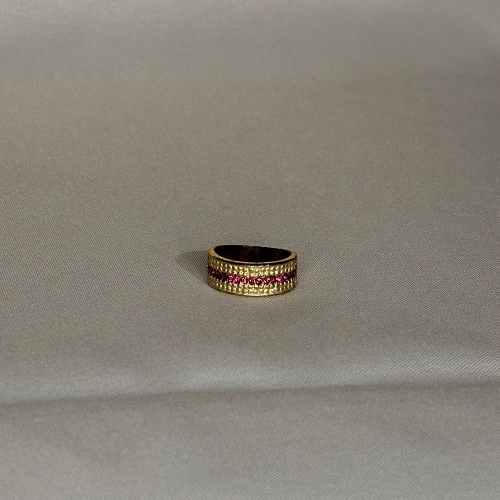 Gold tone ring with textured band and a central row of pink stones.